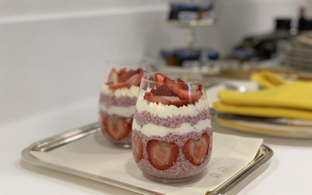 Taças de chia pudding de morango decoradas com chantili e fatias de morango, preparadas pelo Chef Silvio Forech, servidas em uma bandeja de metal.