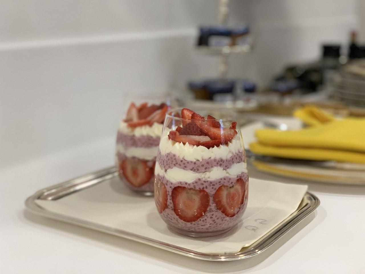 Taças de chia pudding de morango decoradas com chantili e fatias de morango, preparadas pelo Chef Silvio Forech, servidas em uma bandeja de metal.