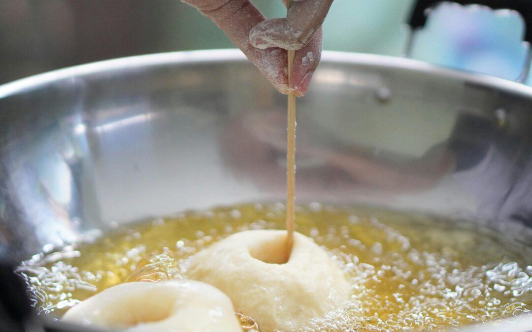 Como fritar massa de forma segura, massa sendo frita em óleo quente com palito de madeira para verificar o cozimento