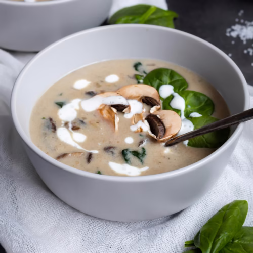 Sopa cremosa de cogumelos com espinafre servida em tigela branca