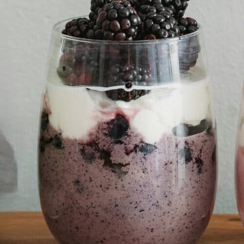 Pudding de chia roxo com frutas frescas e geleia de amora servido em copo de vidro