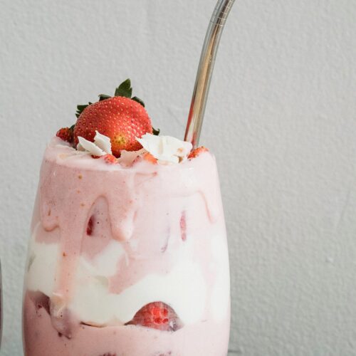 Copo de smoothie de morango em camadas com iogurte e morangos frescos